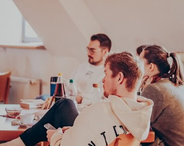 Vier Personen sitzen an einem Tisch, sprechen und hören zu.