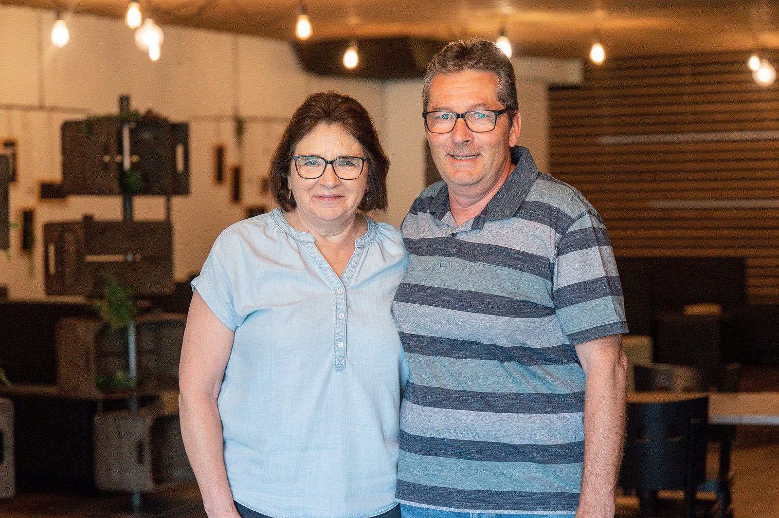 Ein Mann und eine Frau mit Brillen stehen nebeneinander in einem Restaurant.