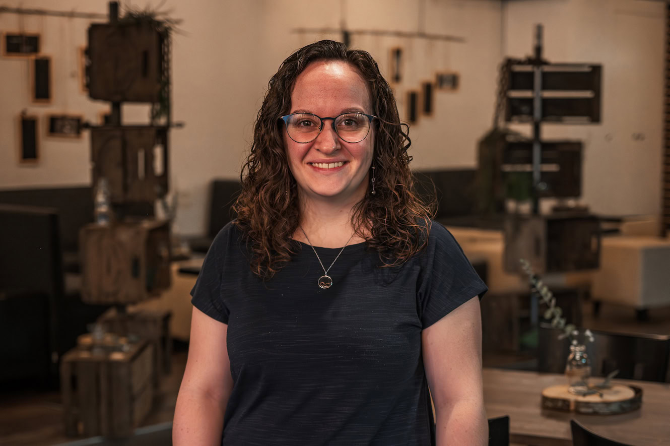 Eine Frau mit Brille und lockigem Haar steht in einem Atelier.