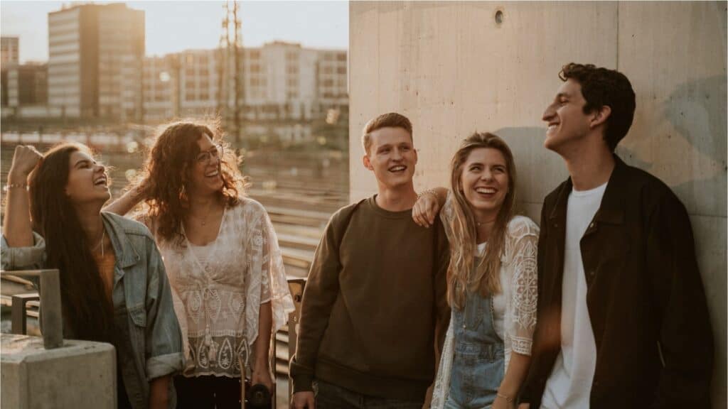 Fröhliche junge Menschen lachen und unterhalten sich in lockerer Atmosphäre vor der Kirche in München.