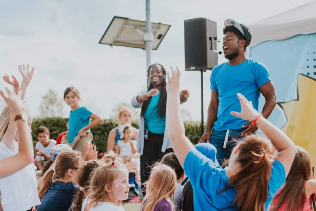 Fröhliche Kinder und Betreuer feiern gemeinsam bei einem outdoor Jugend-Event in München - Spaß, Musik und Gemeinschaft.