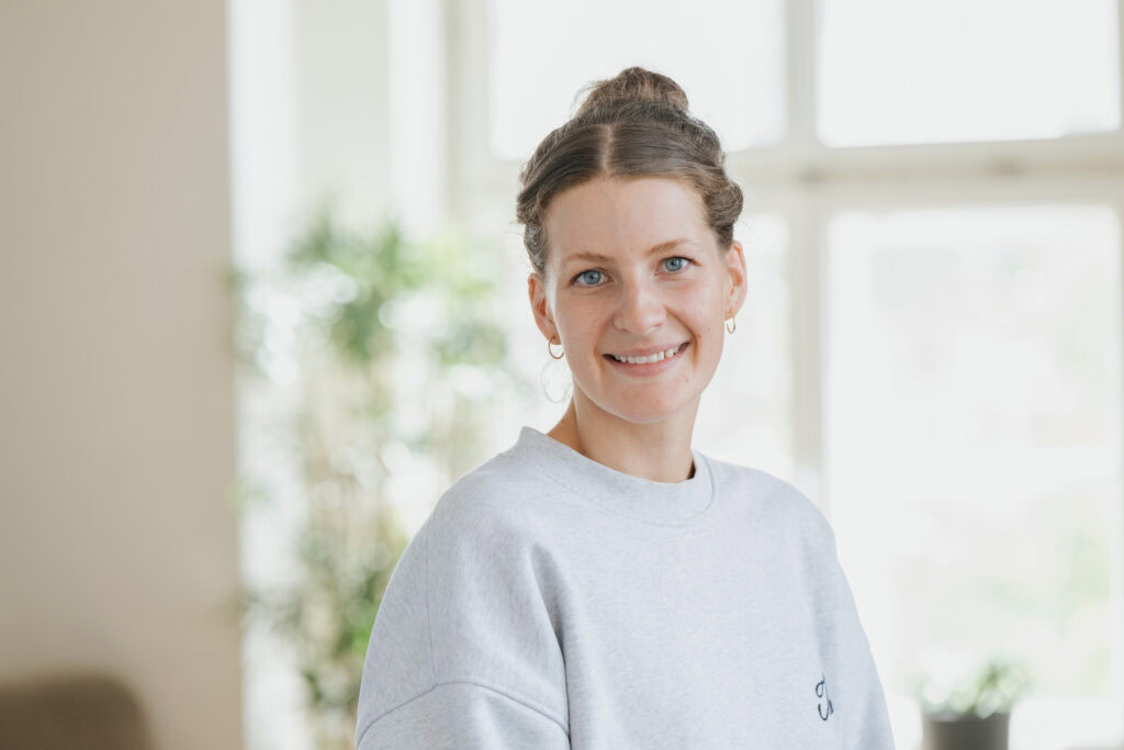 Junge frau mit braunen haaren, die lächelt, im hellen raum.