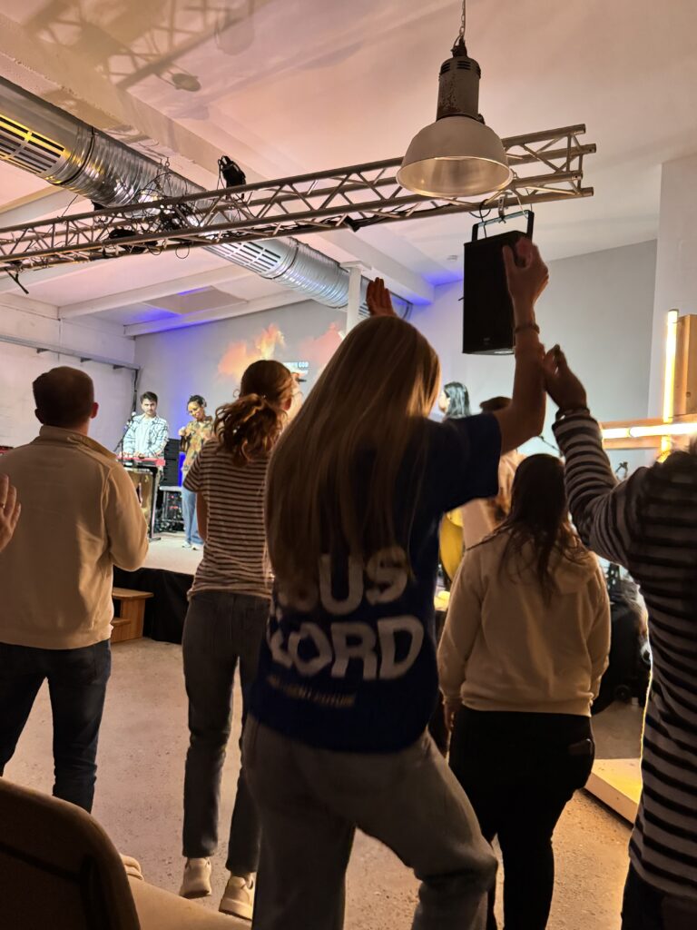 Menschen tanzen und feiern in einem Raum mit Bühne und Musik.