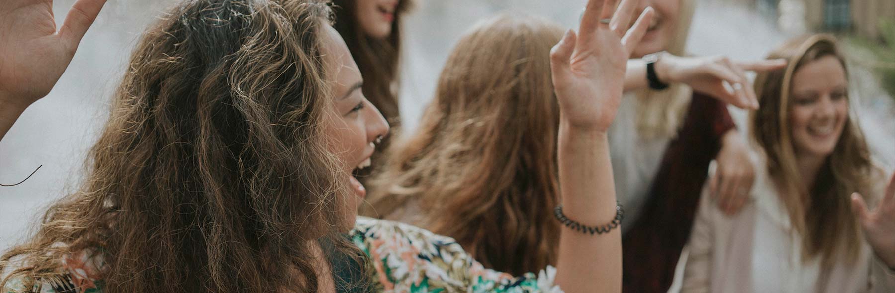 Gruppe junger Frauen lacht und unterhält sich im Freien.