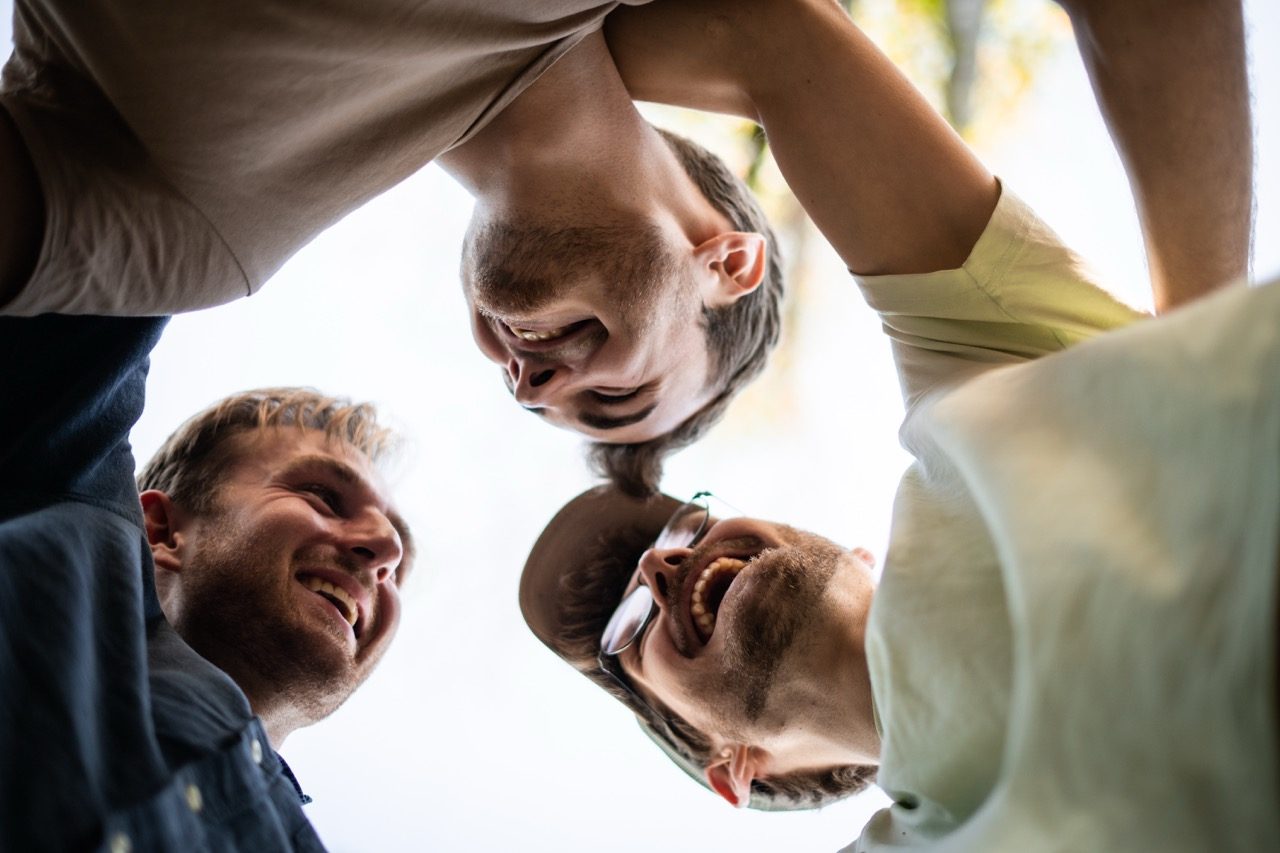 Menschen lachen und umarmen sich, Freude, Gemeinschaft, positive Atmosphäre, freundschaftliche Verbindung, zwischenmenschliche Beziehung, Glücksmoment, Naturhintergrund, fröhliche Stimmung.