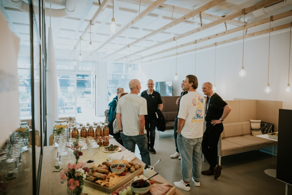 Six people standing and talking in a bright, modern co-working space.
