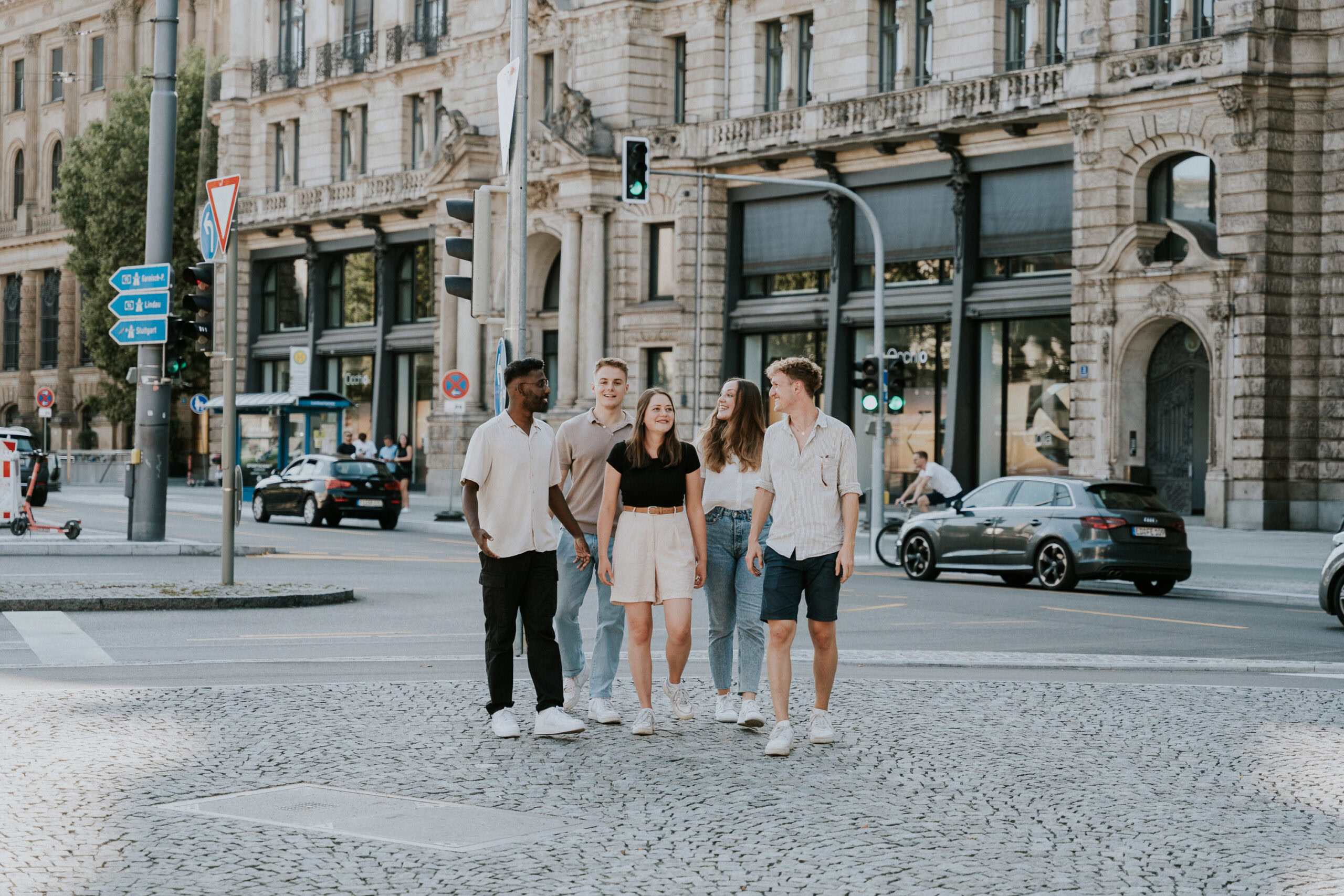 Four young adults walking across a city crosswalk in front of a historic building.