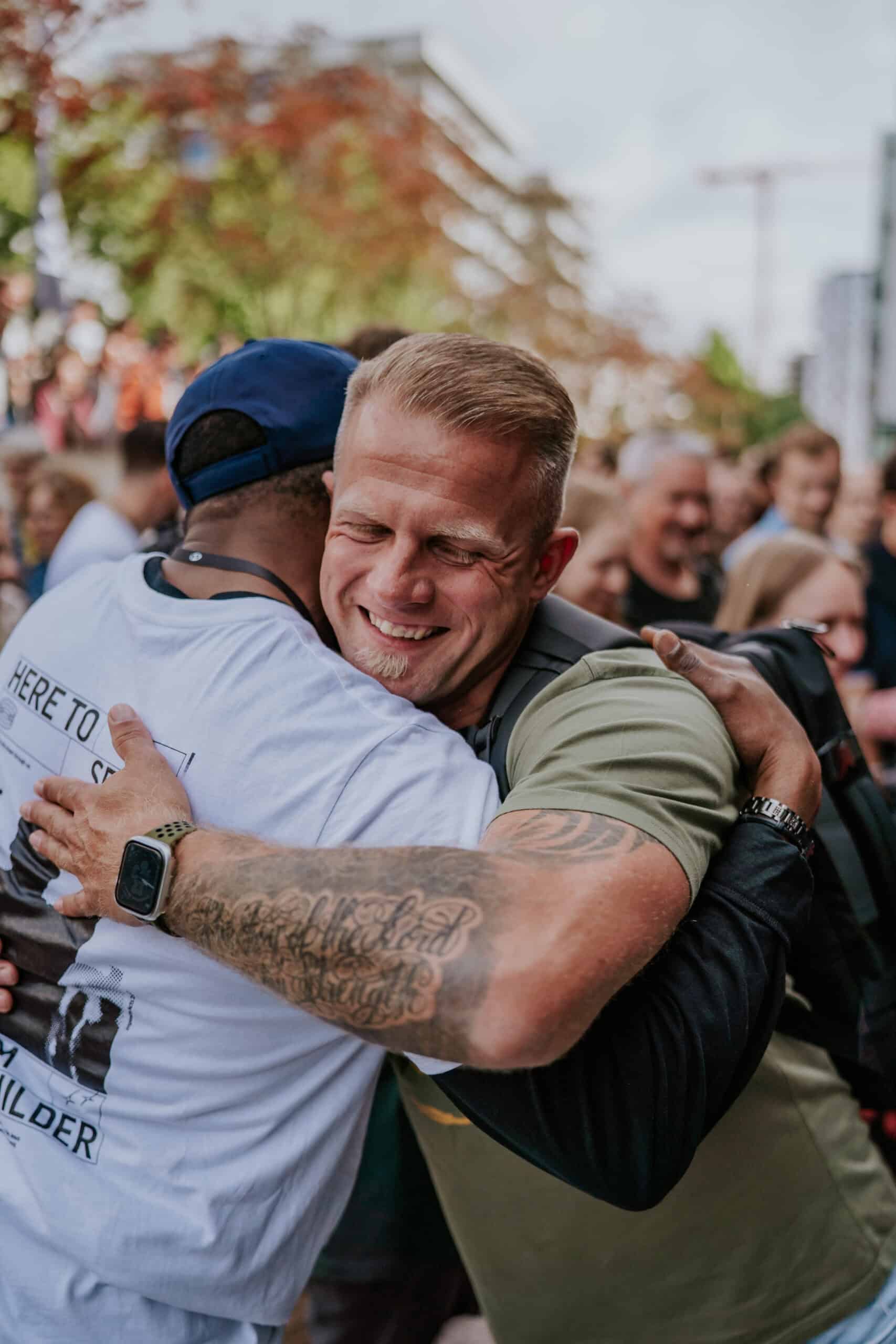 An image of two men hugging in a crowd outdoors.