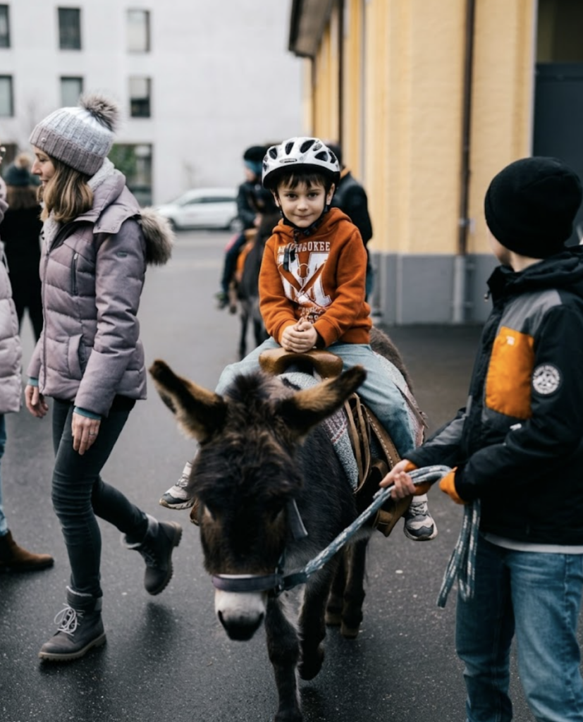 Ein Junge sitzt auf einem Esel, trägt einen Helm, umgeben von Erwachsenen und anderen Kindern.