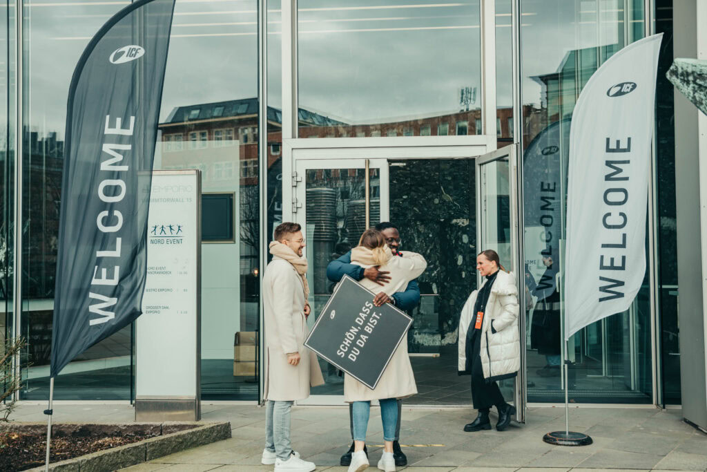 Willkommensgruß beim Event vor dem ICF Gebäude mit freundlichem Austausch und Hallo-Signale.
