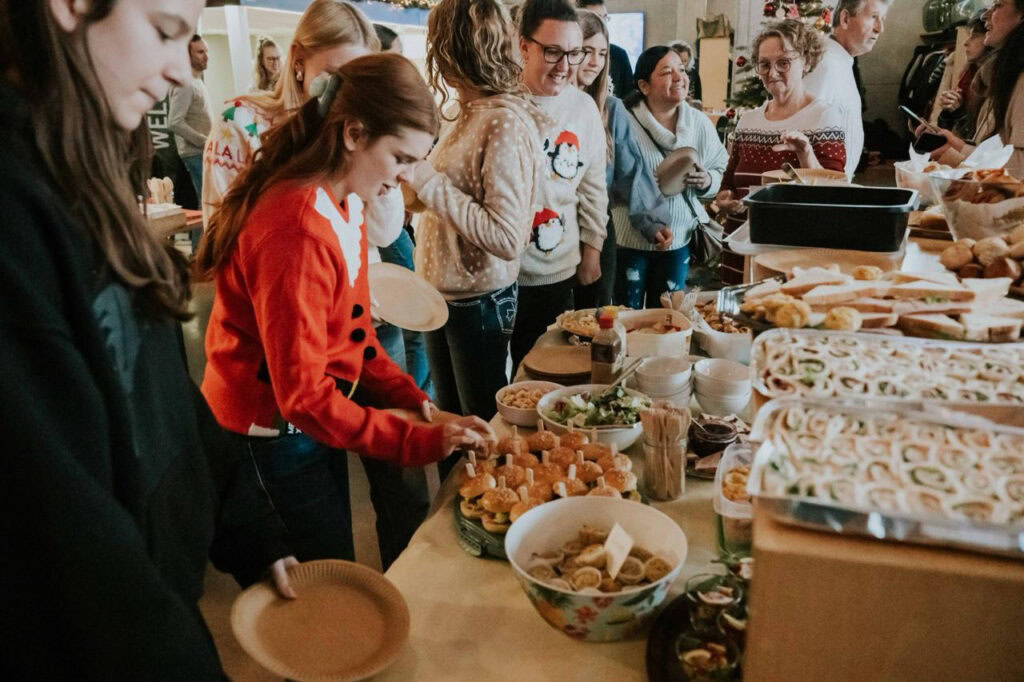 Menschen stehen in einer Schlange vor einem Buffet mit verschiedenen Speisen.