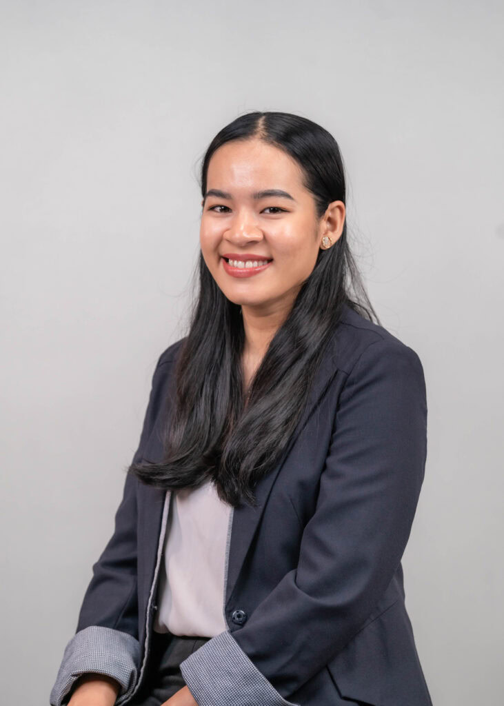 Frau im Business-Outfit bei ICF Siem Reap, lächelnd, professionell, vor neutralem Hintergrund, symbolisiert Engagement und Gemeinschaft.
