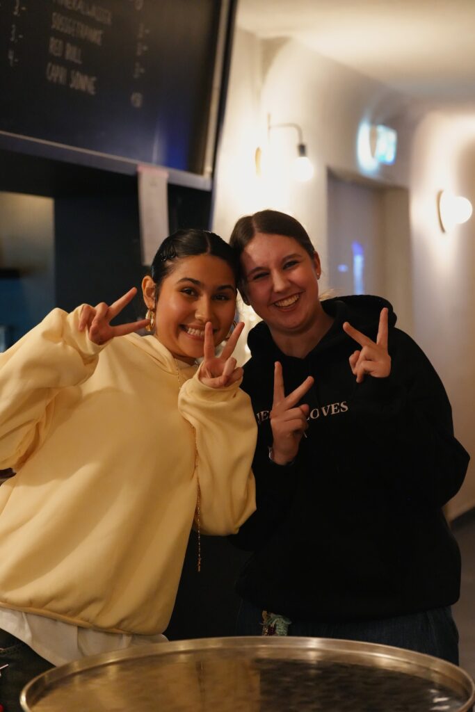 Zwei Frauen zeigen Peace-Zeichen und lächeln in einem Restaurant.