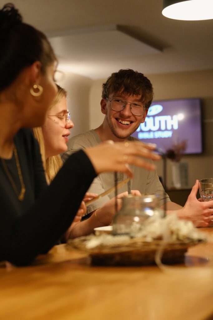 Drei Personen sitzen an einem Tisch, lachen und unterhalten sich.