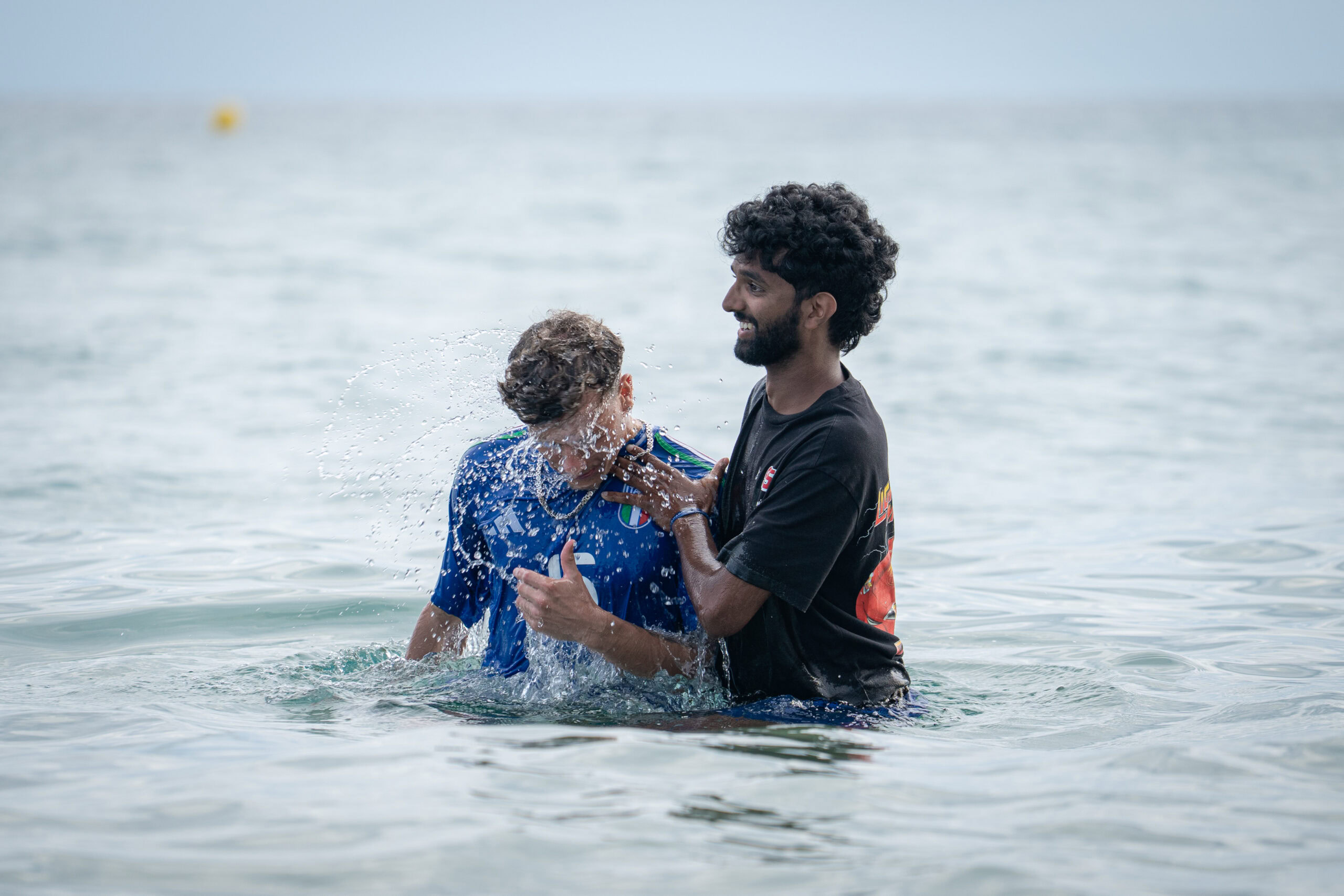 Ein Mann hält ein Kind im Wasser, während sie im Meer stehen.