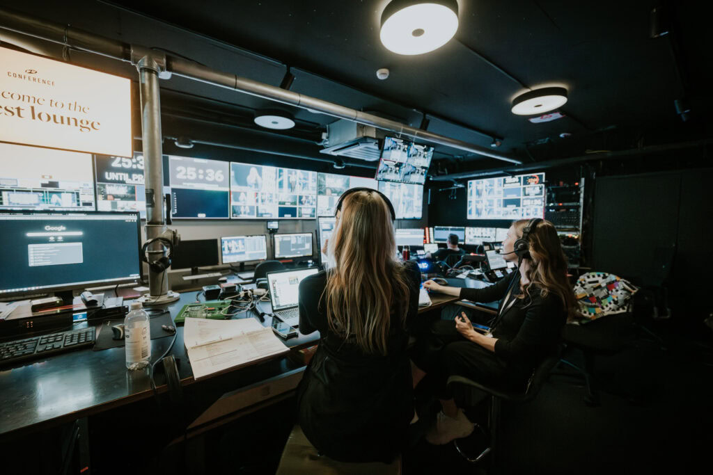 Fernsehregie mit mehreren Monitoren, Mitarbeitern im Einsatz, professionelle Produktion, Medien, Live-Übertragung, Medienzentrum.