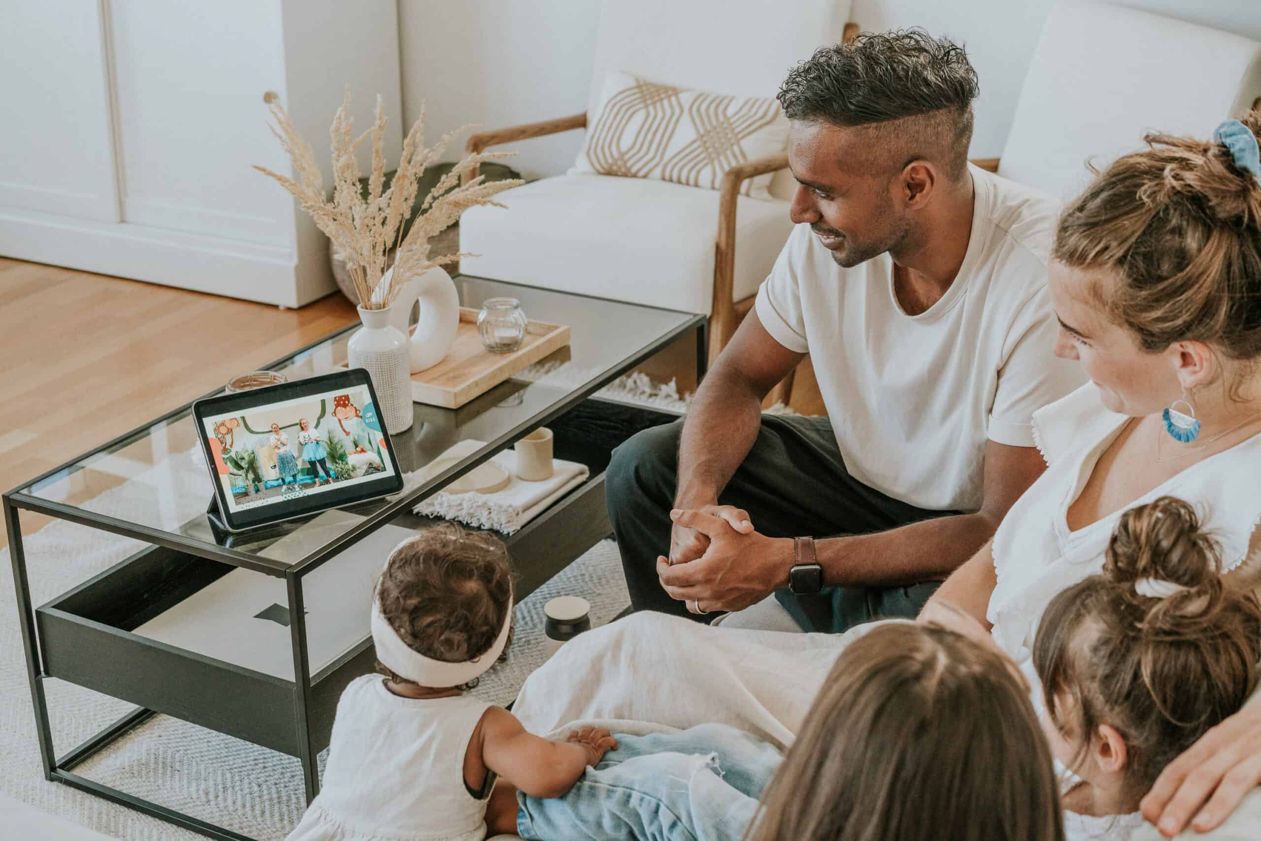 Familie schaut virtuelles Kinderprogramm auf einem Tablet zu, im Wohnzimmer, digital verbunden, gemeinsames Streaming, Familienaktivität, entspannt, moderne Technologie, Freizeitgestaltung, Freizeit, Zuhause, Videoanruf, Online-Kinderprogramm.