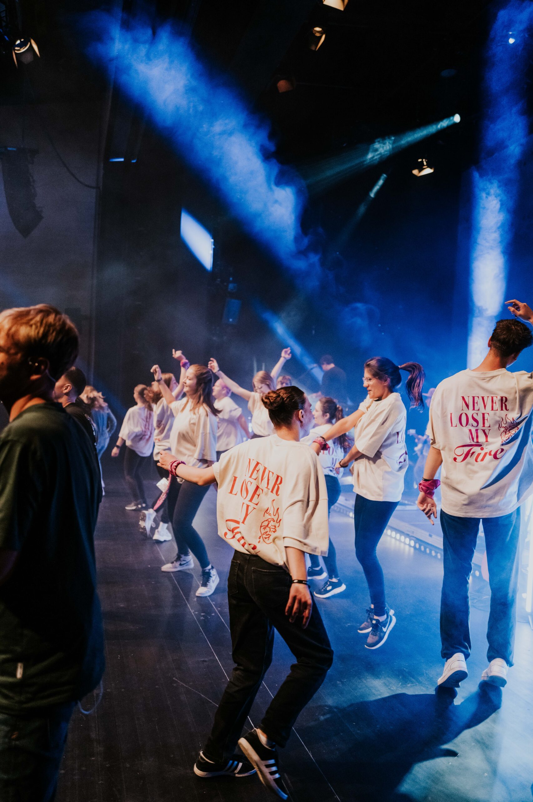 Jugendliche und junge Erwachsene tanzen bei einer lebhaften Gemeinschaftsveranstaltung in der Kirche ICF Schwarzwald Bodensee, umgeben von buntem Licht und einer positiven Atmosphäre.