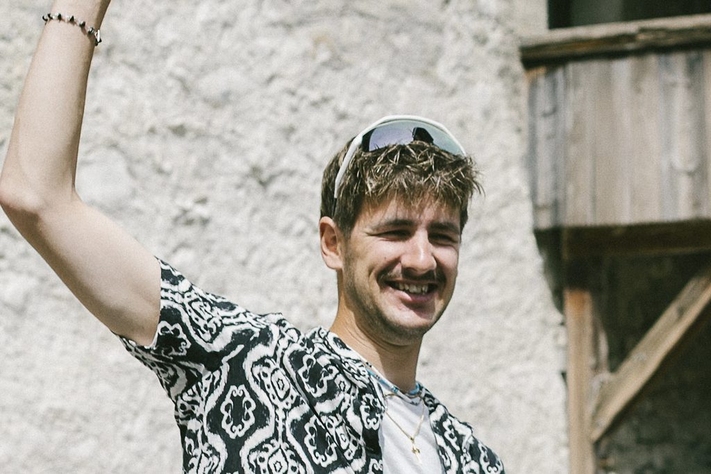 Mann mit sunglasses und mustermuster-shirt hebt die hand.