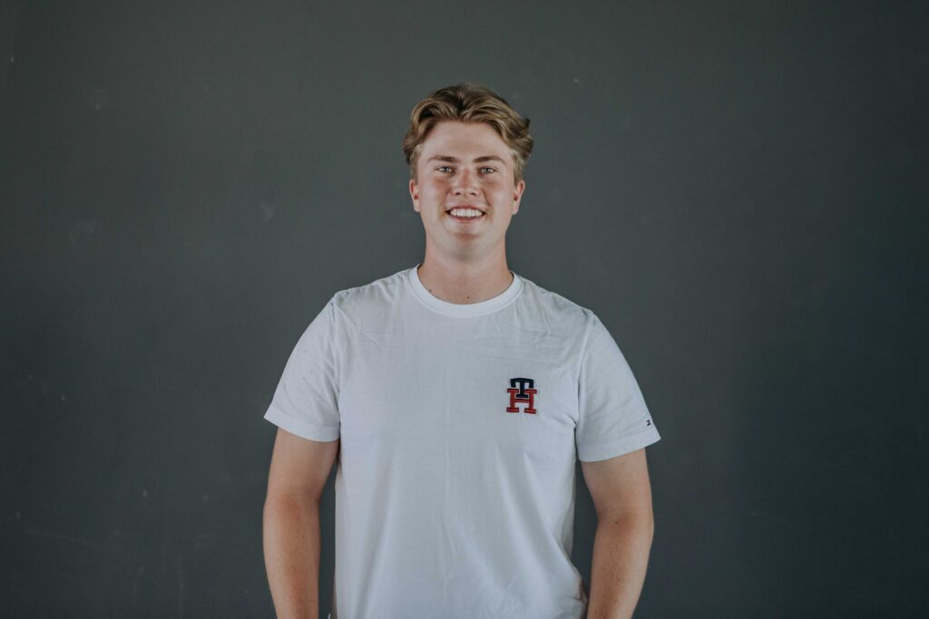 Junge Person in weißem T-Shirt vor grauem Hintergrund.