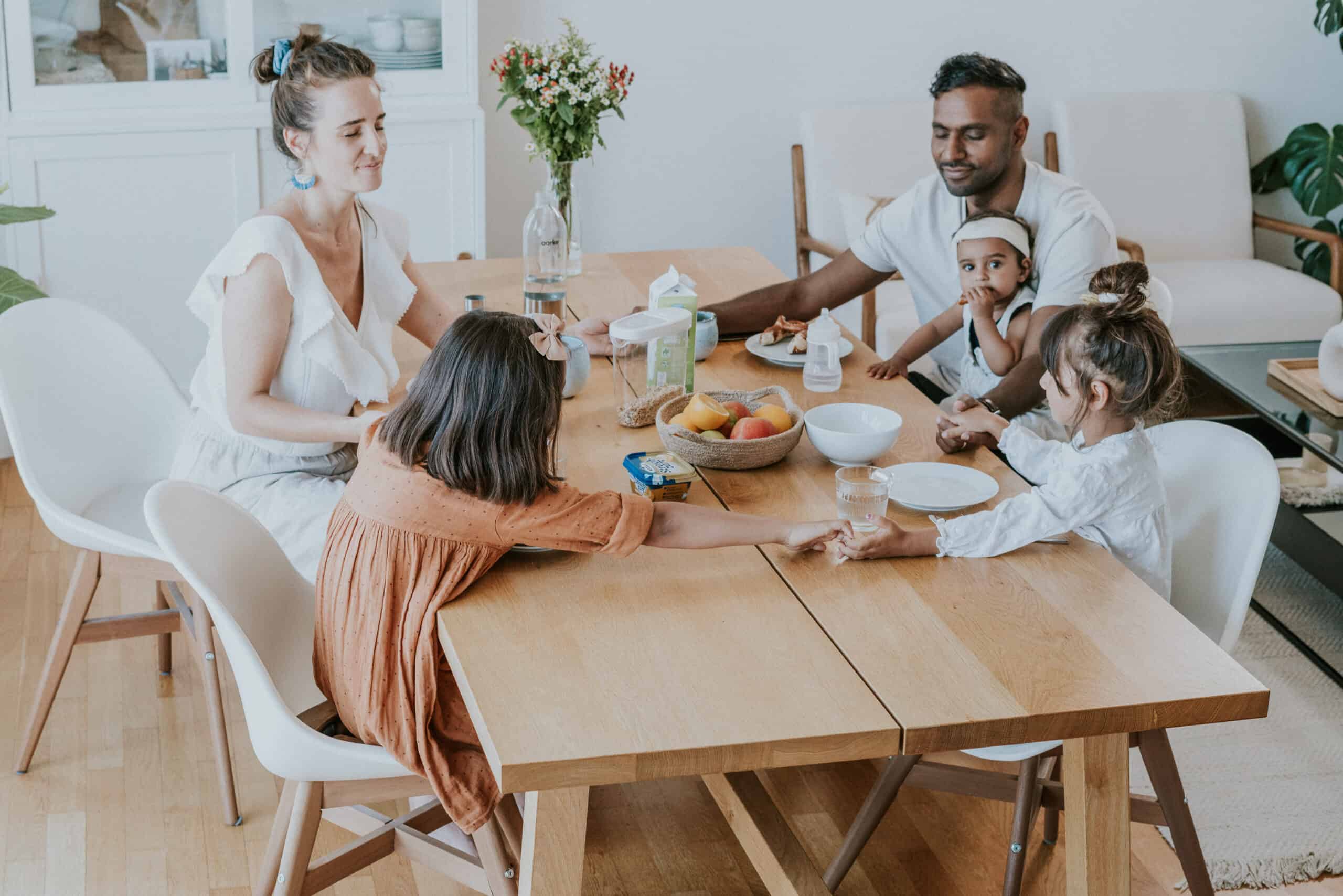 Ein multikulturelles Familienfrühstück zu Hause mit Eltern und Kindern, gesundes Essen, liebevolle Momente, gemeinsames Frühstück, moderne Einrichtung, Kindersicherheit, Eltern-Kind-Bindung, Familienzeit, entspannter Morgen, Koch- und Essenszeit.