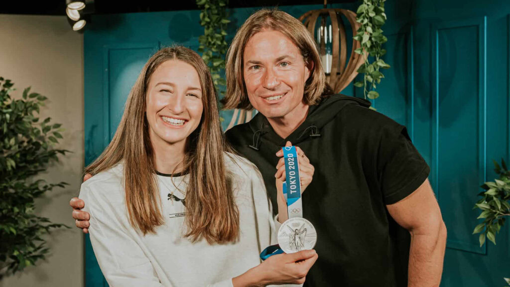 Zwei Menschen, eine Frau und ein Mann, halten eine Medaille.