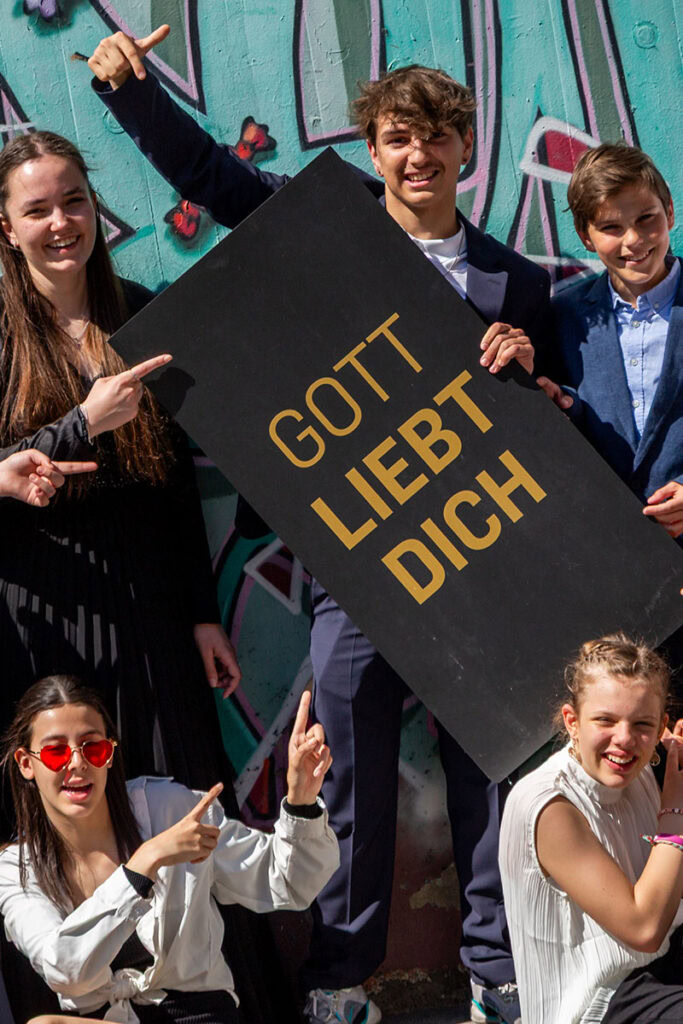 Gruppe von Menschen, die im Freien bei Sonnenlicht eine Demonstration halten, mit einem schwarzen Sc.
