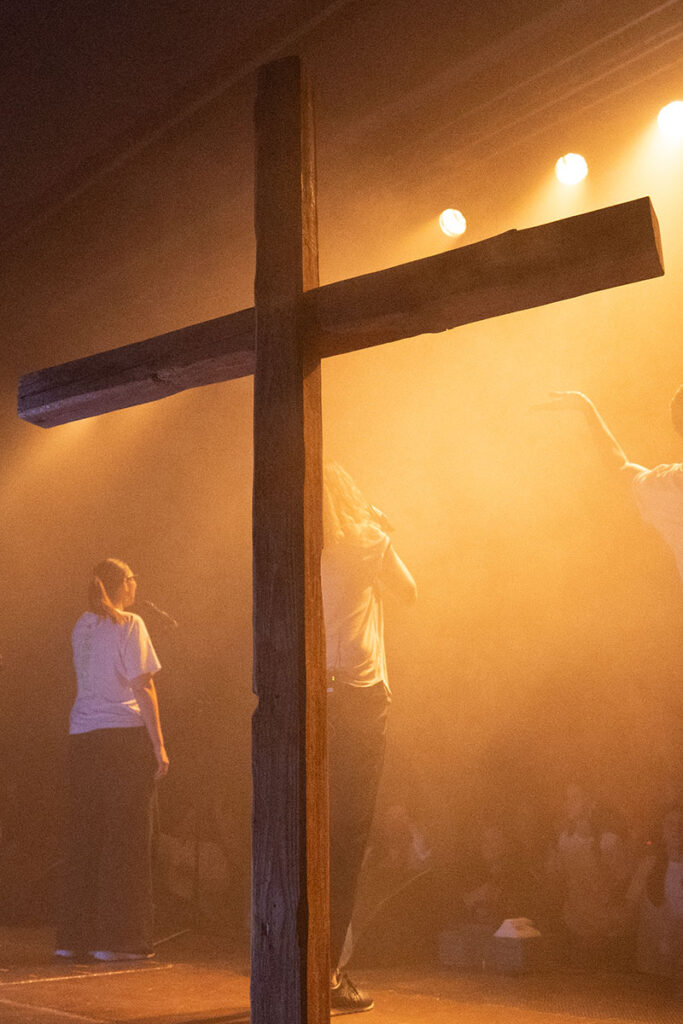 Großes Holz-Kreuz im Licht bei einem Gottesdienst.