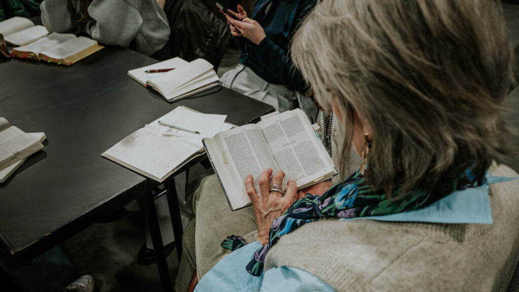 Frau liest in einer Bibel während einer Gruppendiskussion.