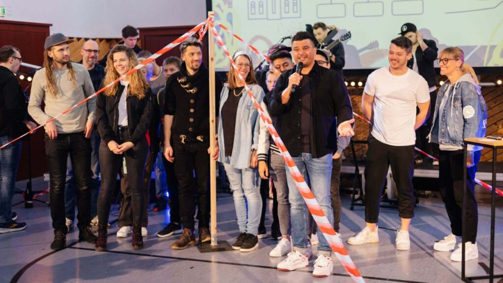 Gruppe von Menschen auf Bühne, einige sprechen, andere hören zu.