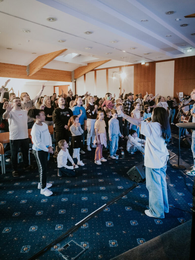 Kinder und Erwachsene singen und tanzen im Gottesdienst.