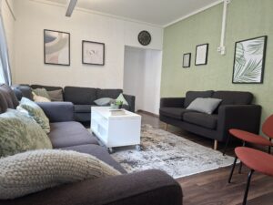 Ein Wohnzimmer mit mehreren Sofas, einem weißen Couchtisch und Wanddekorationen.