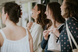Vier Frauen stehen nebeneinander, lachen und sprechen miteinander.