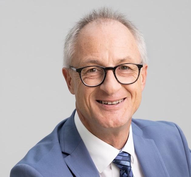 Ein freundlicher Pastor in formellem Anzug, der in einer Kirche oder Gemeinde in Basel, Schweiz, spricht, um die Mission und den Glauben der ICF Basel zu fördern.