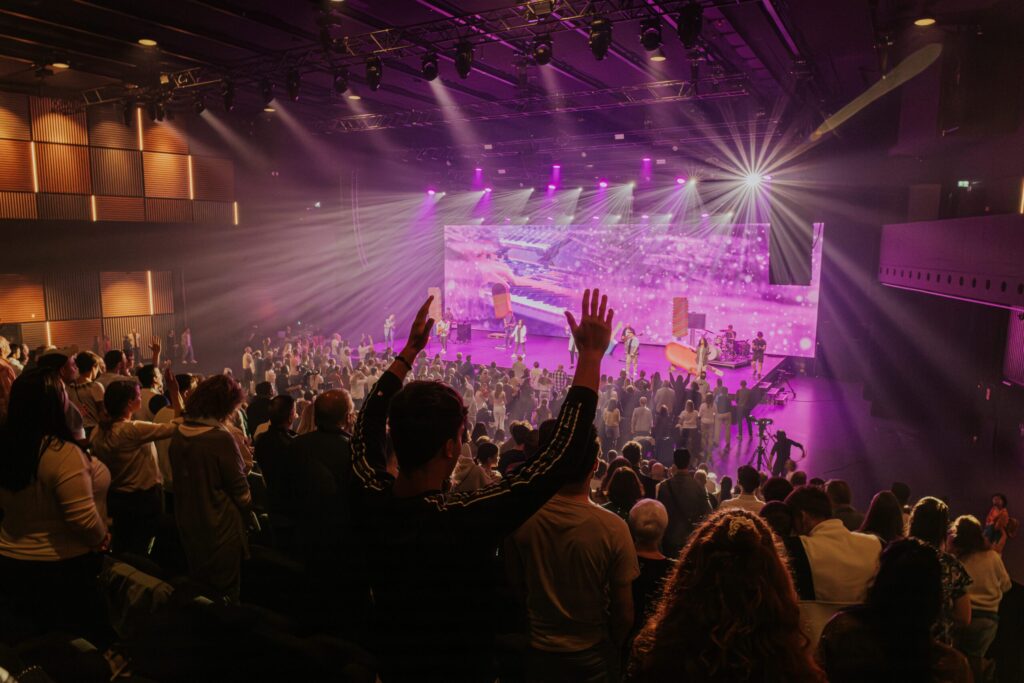 A large stage with a colorful, bright LED wall in the background, musicians performing.