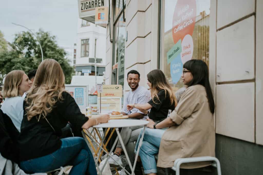 Menschen sitzen draußen vor einem Café, plaudern und essen.