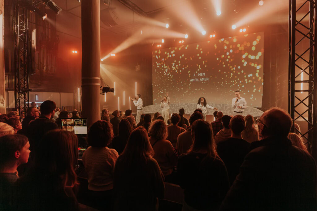 Gejochte zaal met een podium en muzikanten terwijl een menigte kijkt.