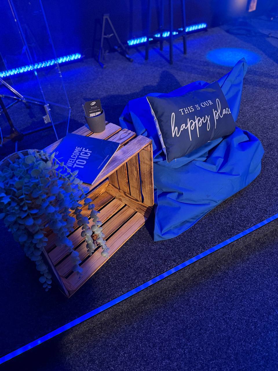 Pohovka s polštářem a stolkem na podlaze, osvětlené modrým světlem.