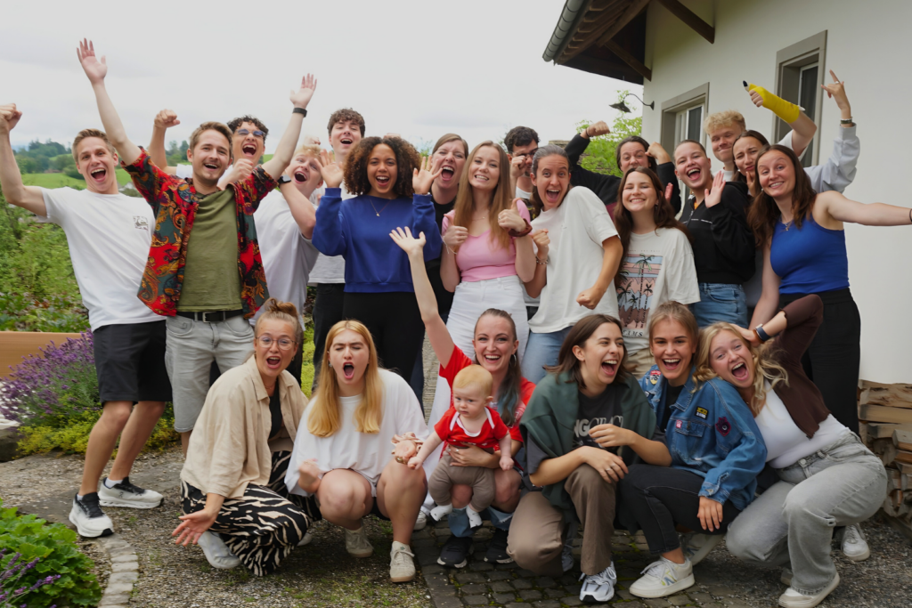 Gruppe von Menschen, die draußen vor einem Haus lachen und feiern.