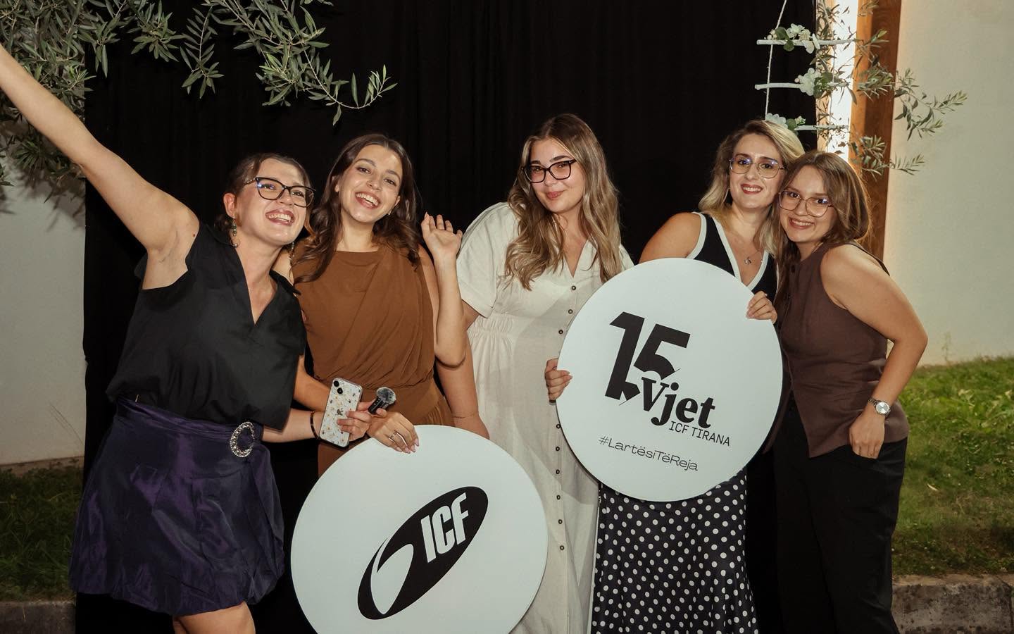 Five women standing outdoors, holding ICF and 15 Vjet signs, smiling at the camera.