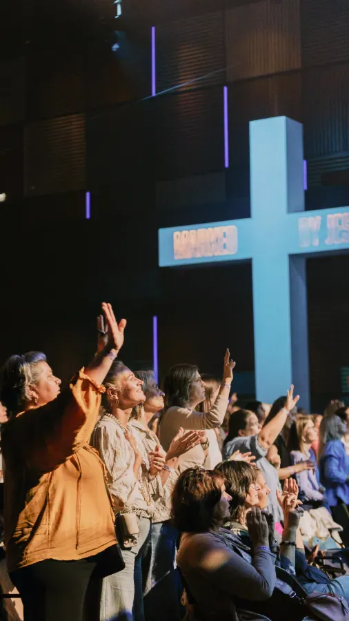 Menschen in einer Kirche beten und heben die Hände.