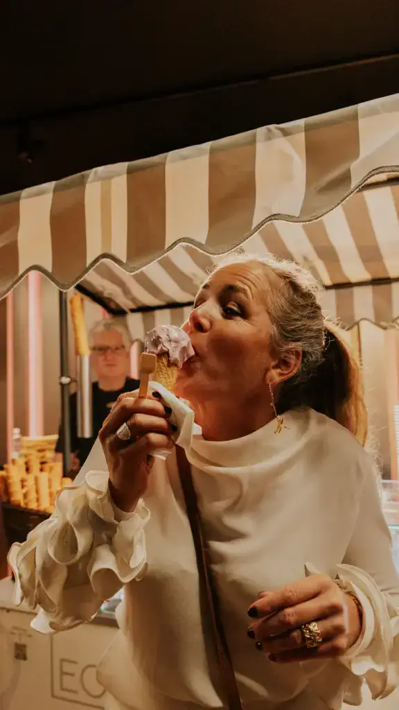Frau isst ein Glace an einem Stand im Foyer.