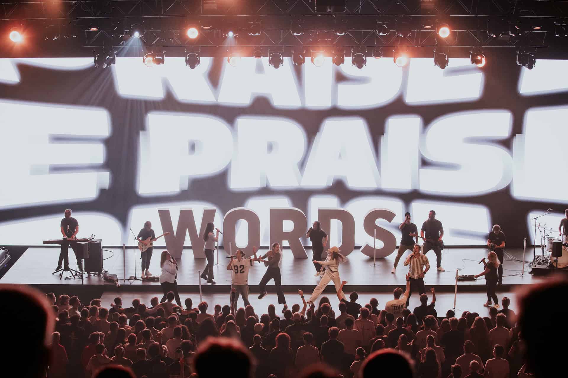 People on stage in front of a large screen with text.