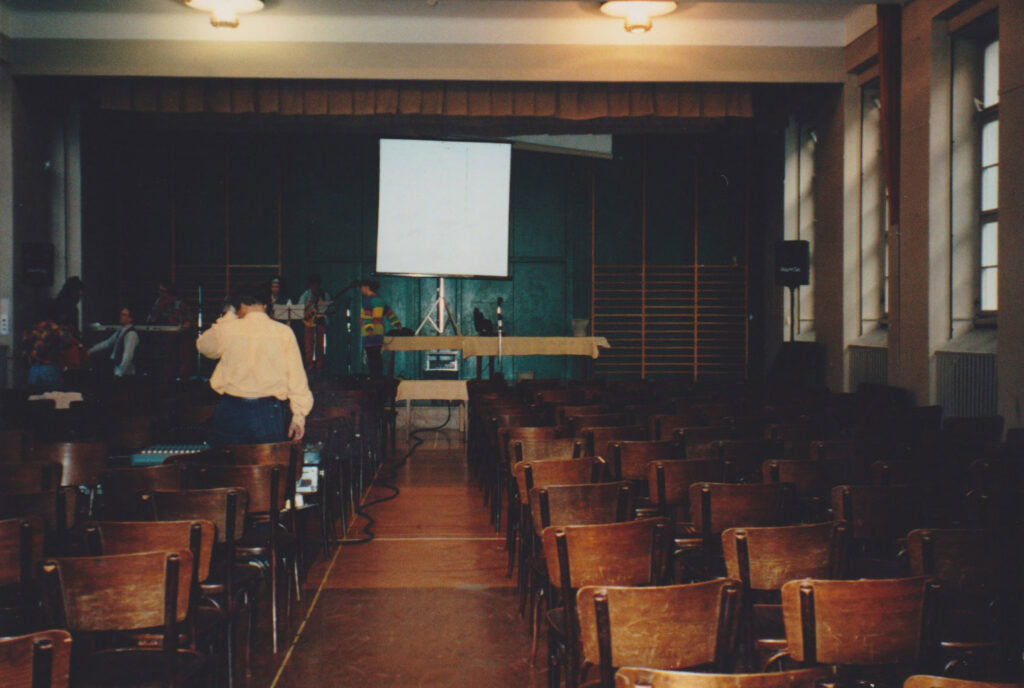 Leerer Saal mit Stühlen, Projektor und Leinwand an der Wand.