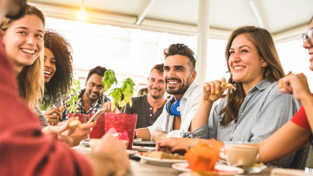 Mehrere Menschen sitzen an einem Tisch, lachen und unterhalten sich.