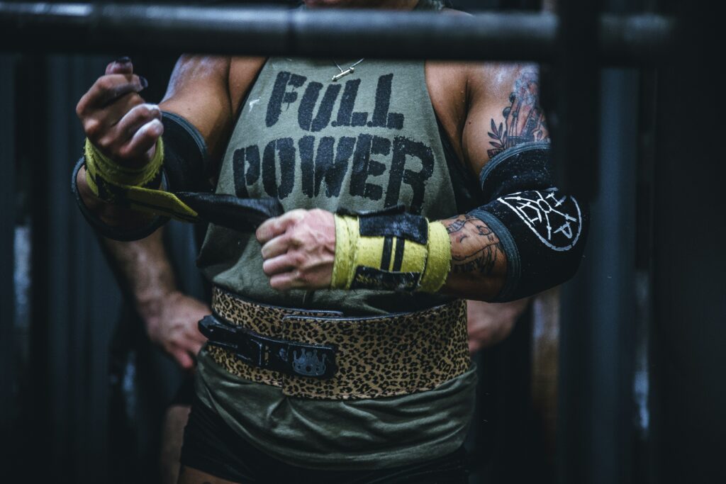 Frau mit Tattoos, Sportbekleidung und Armbändern beim Krafttraining.