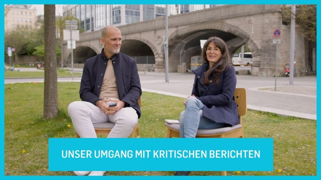 Two people sitting on benches in a park, talking.