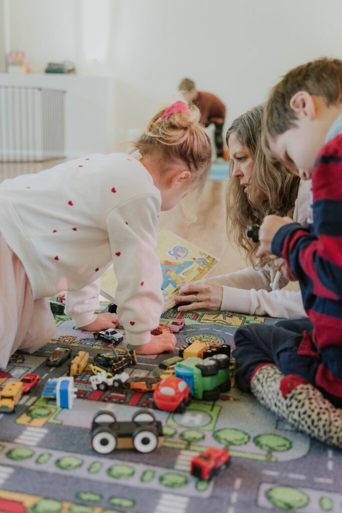 Mehrere Kinder schauen auf die Spielautos, eine Erwachsene ist im Hintergrund.