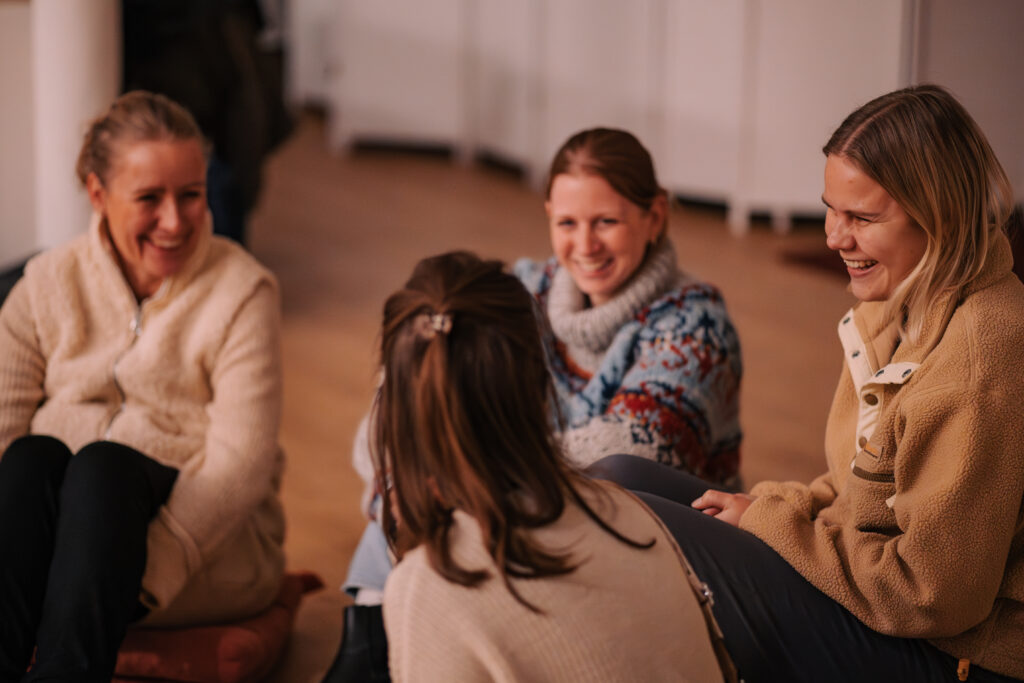 Frauen sitzen im Kreis und unterhalten sich bei einem Gemeinschaftsabend in Hamburg, Deutschland.