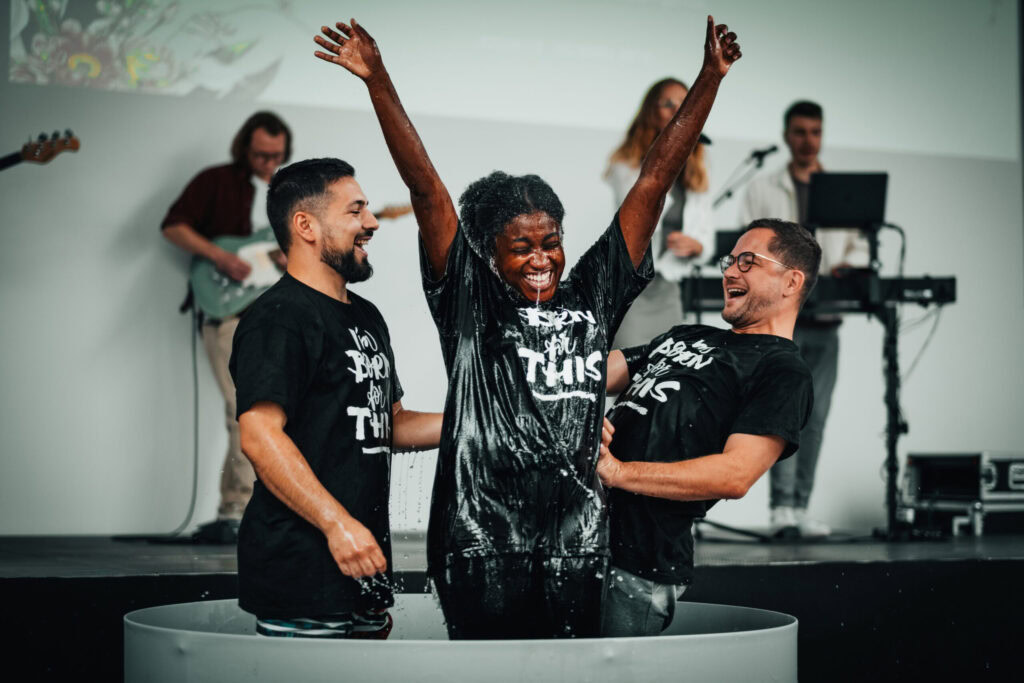 Junge Menschen feiern Taufe mit Wasser im Baptismal und erleben Gemeinschaft bei ICF Mannheim, Deutschland.